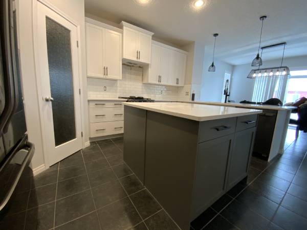 White painted kitchen with accent dark grey island and contrasting hardware