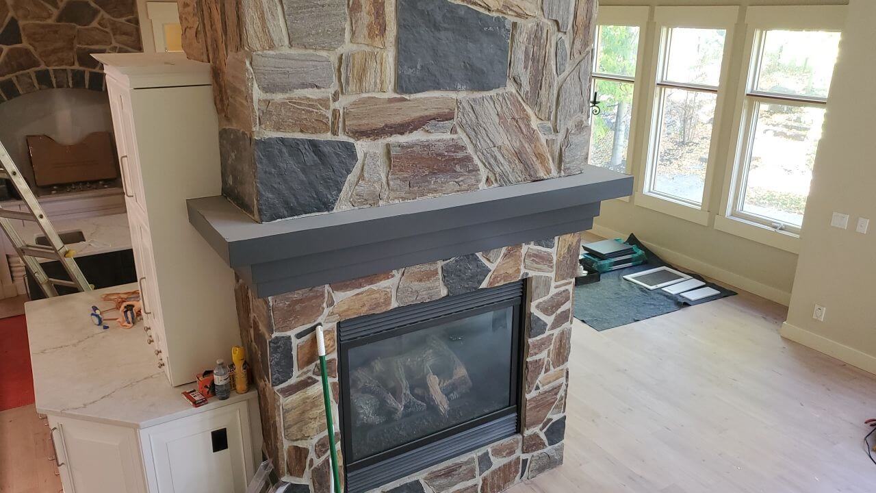 Stylish grey accent mantel on rock tower fireplace