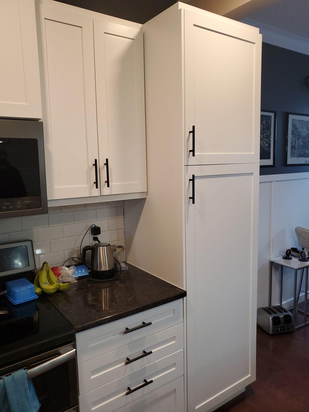 Vibrant white painted cabinetry tower with black hardware in Cochrane