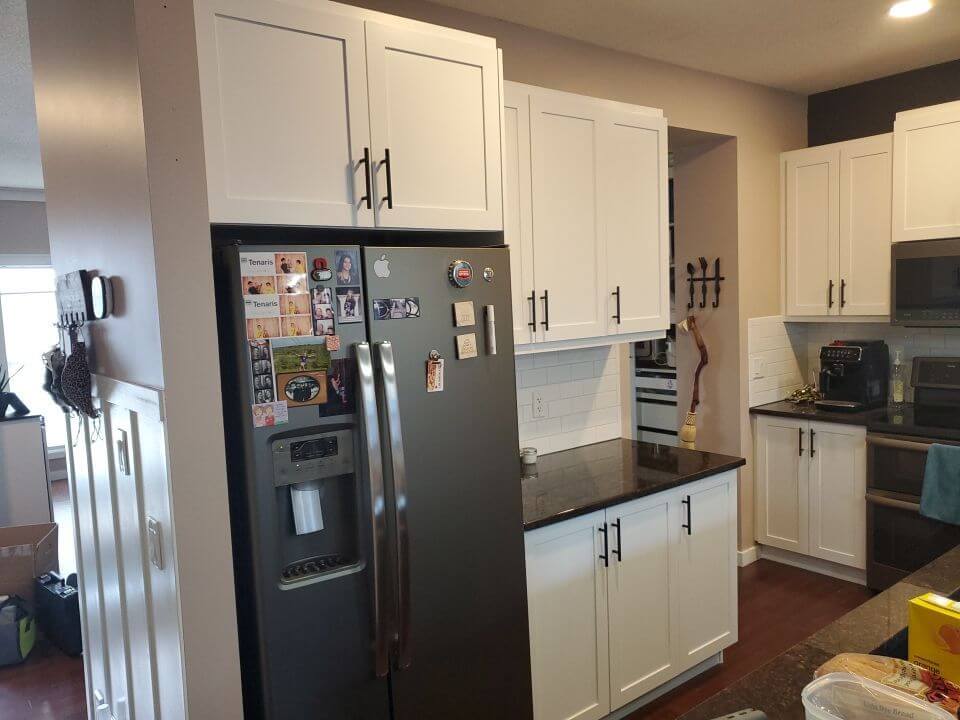 Corner view white painted cabinetry with black hardware