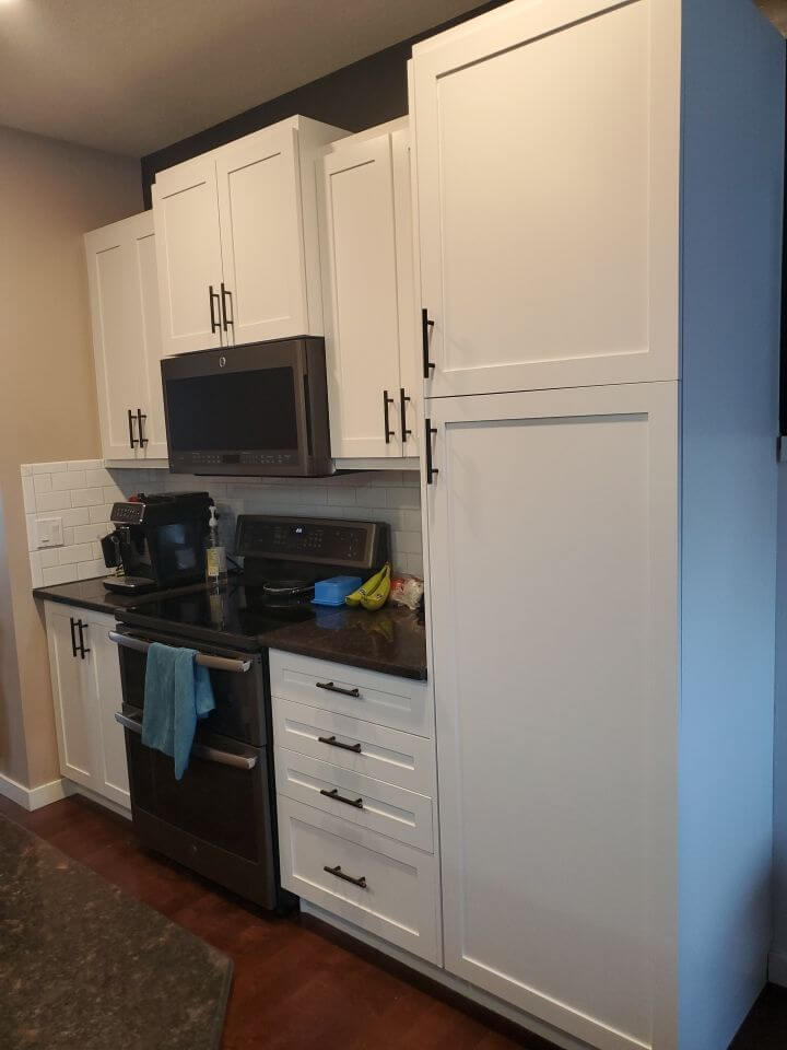 Pantry tower painted bright white with black hardware