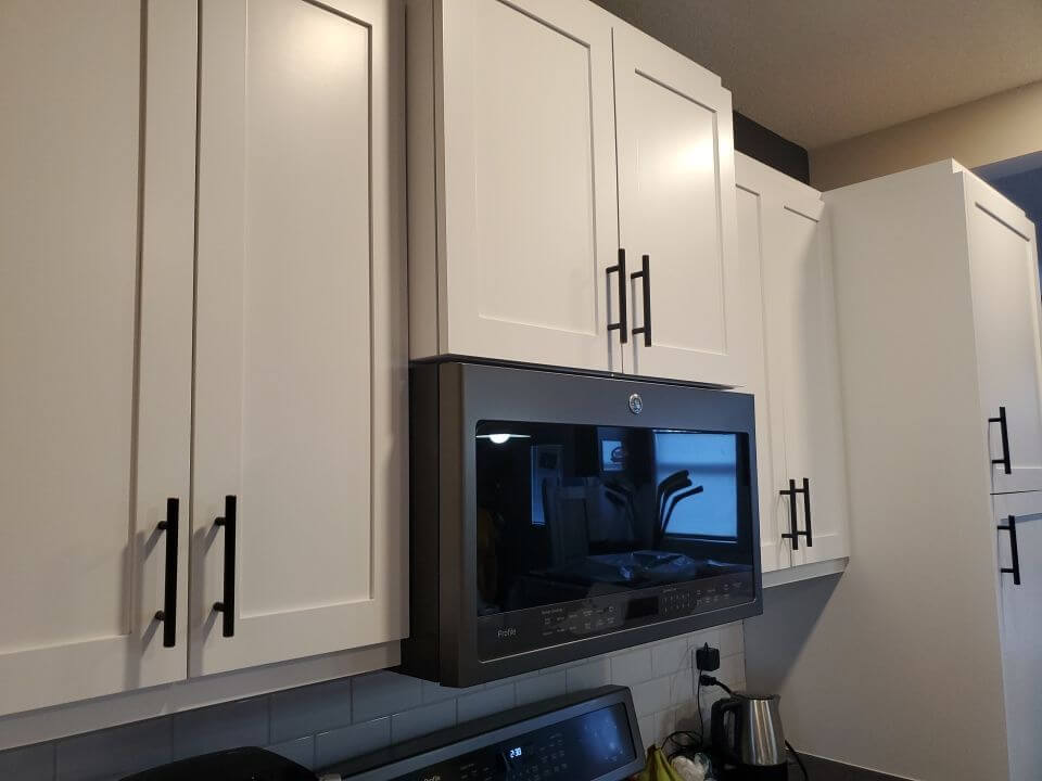 White painted upper cabinets with black accent hardware