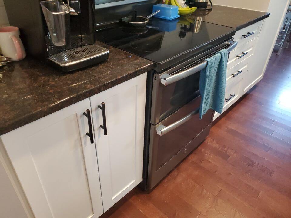 White painted lower cabinetry with dark countertops and black hardware