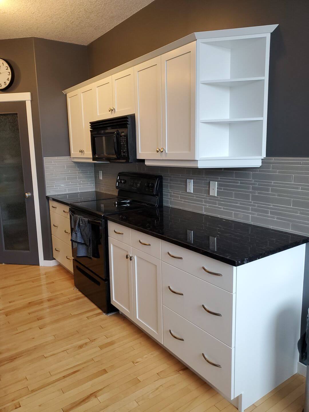 Modern white cabinets with dark appliances, walls and counter tops