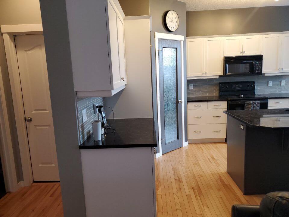 Chic white cabinets with dark island and pantry door accent