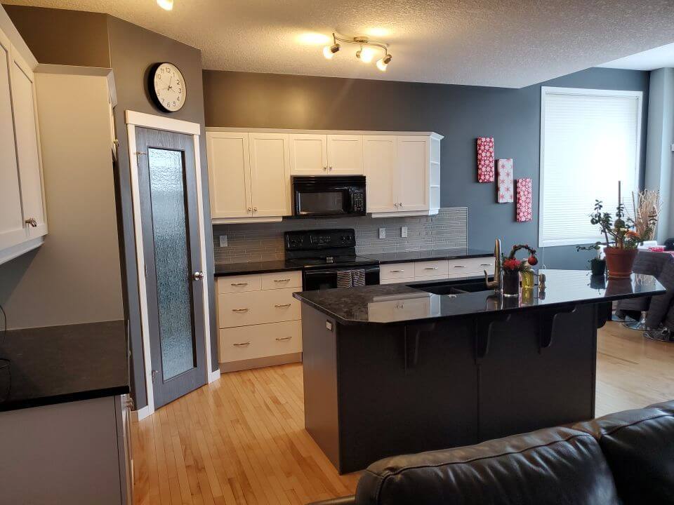 Open white painted kitchen with dark grey accent island and walls